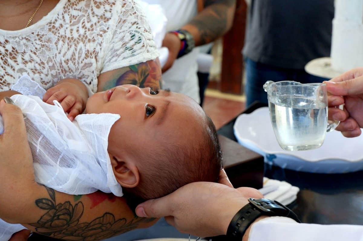 Comment bien choisir une médaille de baptême ? Bébé qui se fait baptiser dans les bras d'une femme